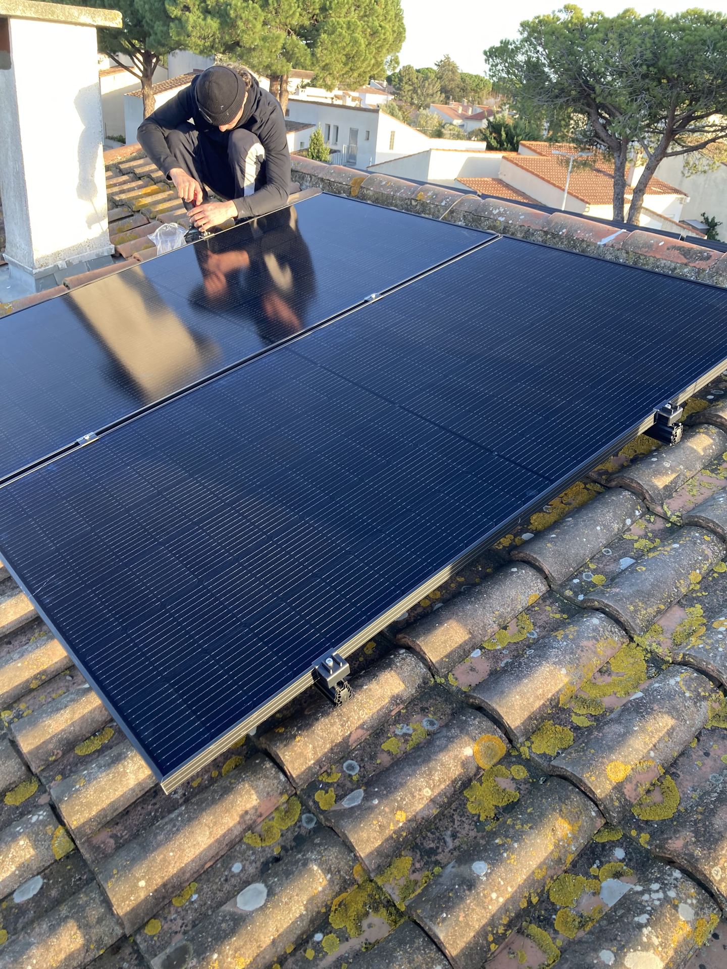 Un technicien ORIA France pose des panneaux solaires sur un toit de tuiles